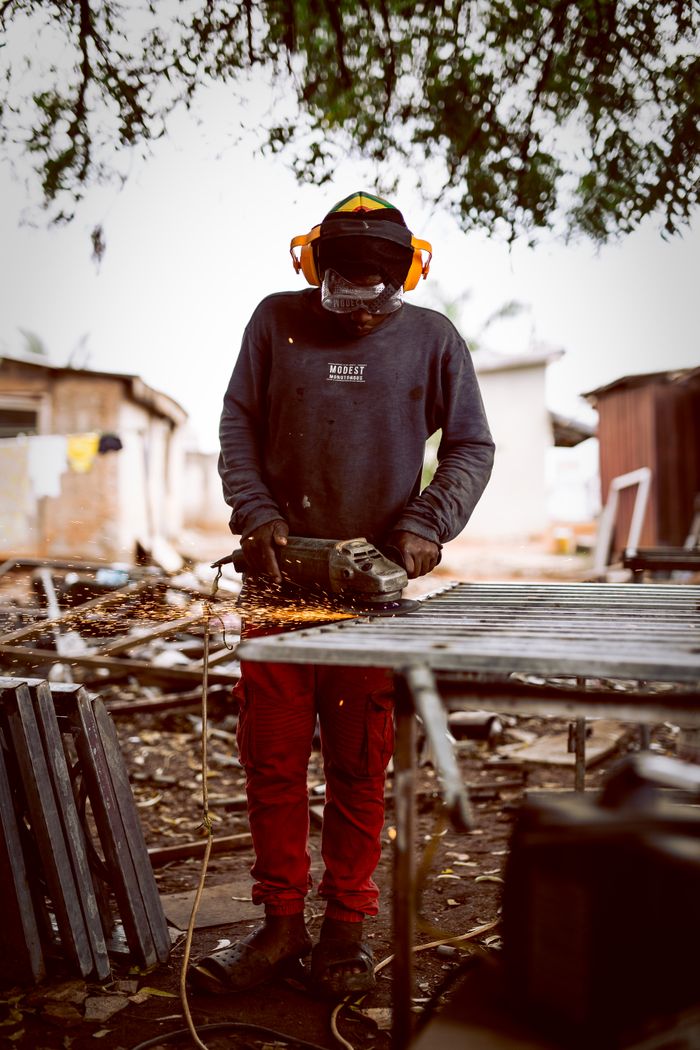 A welder actively working with sparks flying in an outdoor setting, showcasing metal fabrication skills.
