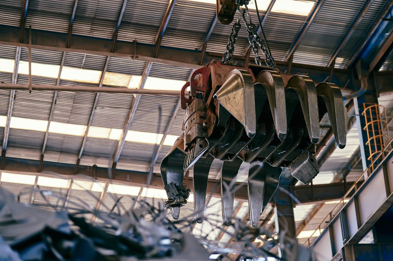 Large industrial crane handling scrap metal in a warehouse setting.